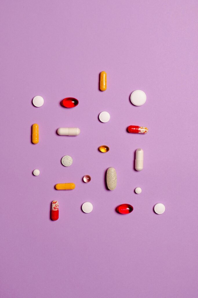 Variety of pills and capsules arranged on a purple surface, showcasing different medications.